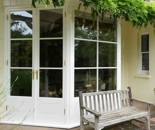 Traditional-style French patio doors, by The Sash Window Workshop, painted white, on a yellow-rendered period-style property.