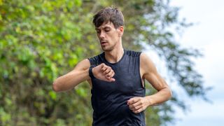 Man checking sports watch while running outdoors