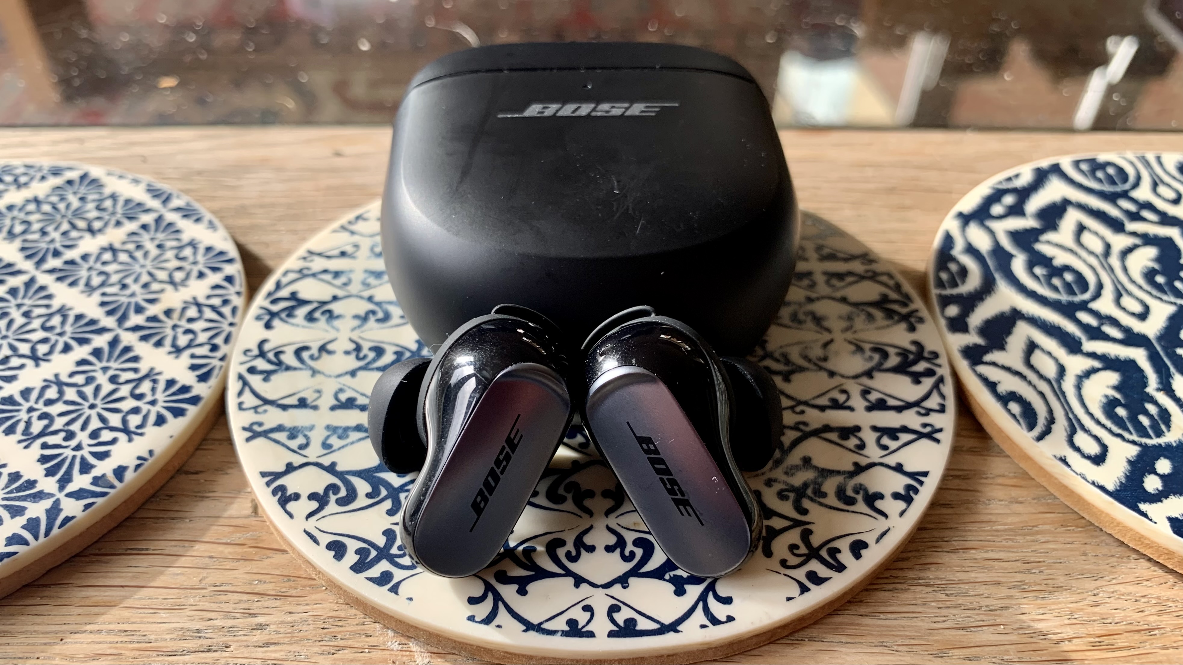 Bose QuietComfort Ultra Earbuds on a coffee table, with the case