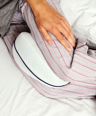 person sleeping with knee pillow between their legs