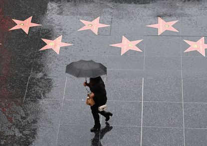A person walks in the rain on Hollywood Boulevard.