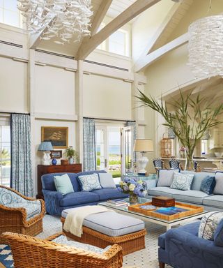living room with white walls and blue sofas and basket chairs and fish light sculpture