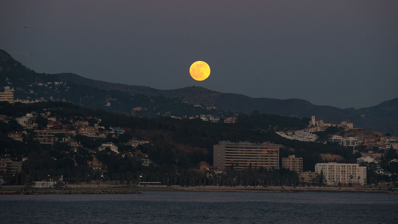 The Full Wolf Moon rises over the horizon at the beach in Malaga, Spain, on Jan. 10, 2020, during the first lunar eclipse of the year.
