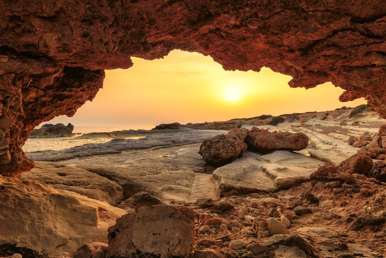 A natural rock arch at sunset on Cyprus&#039;s coast.