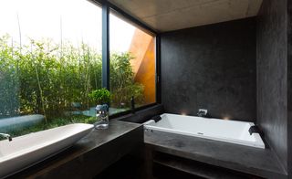 Dark finish for the master bathroom, which looks onto a bamboo-planted garden giving it a tranquil atmosphere