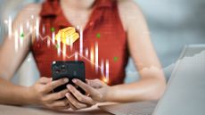 Woman using smartphone overlaid with a graphic showing gold bars and candlestick chart to illustrate mobile trading