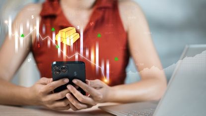 Woman using smartphone overlaid with a graphic showing gold bars and candlestick chart to illustrate mobile trading