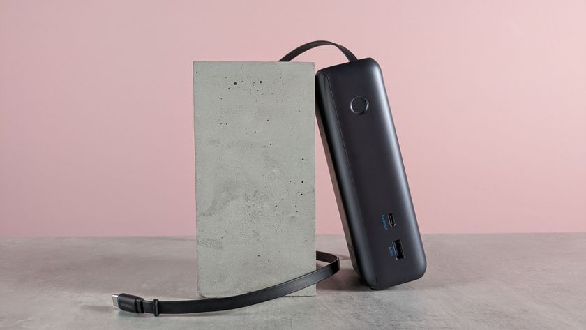 Anker Laptop Power Bank on desk with pink background, retractable cable unraveled