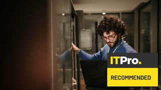 man working on laptop in server room