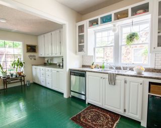 A classic white kitchen with green painted wood flooring