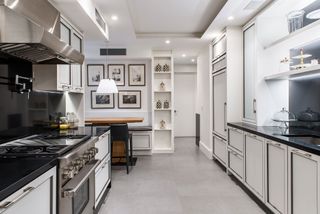 kitchen with white cabinets and black worktopspale floor with view to eating space and gallery wall