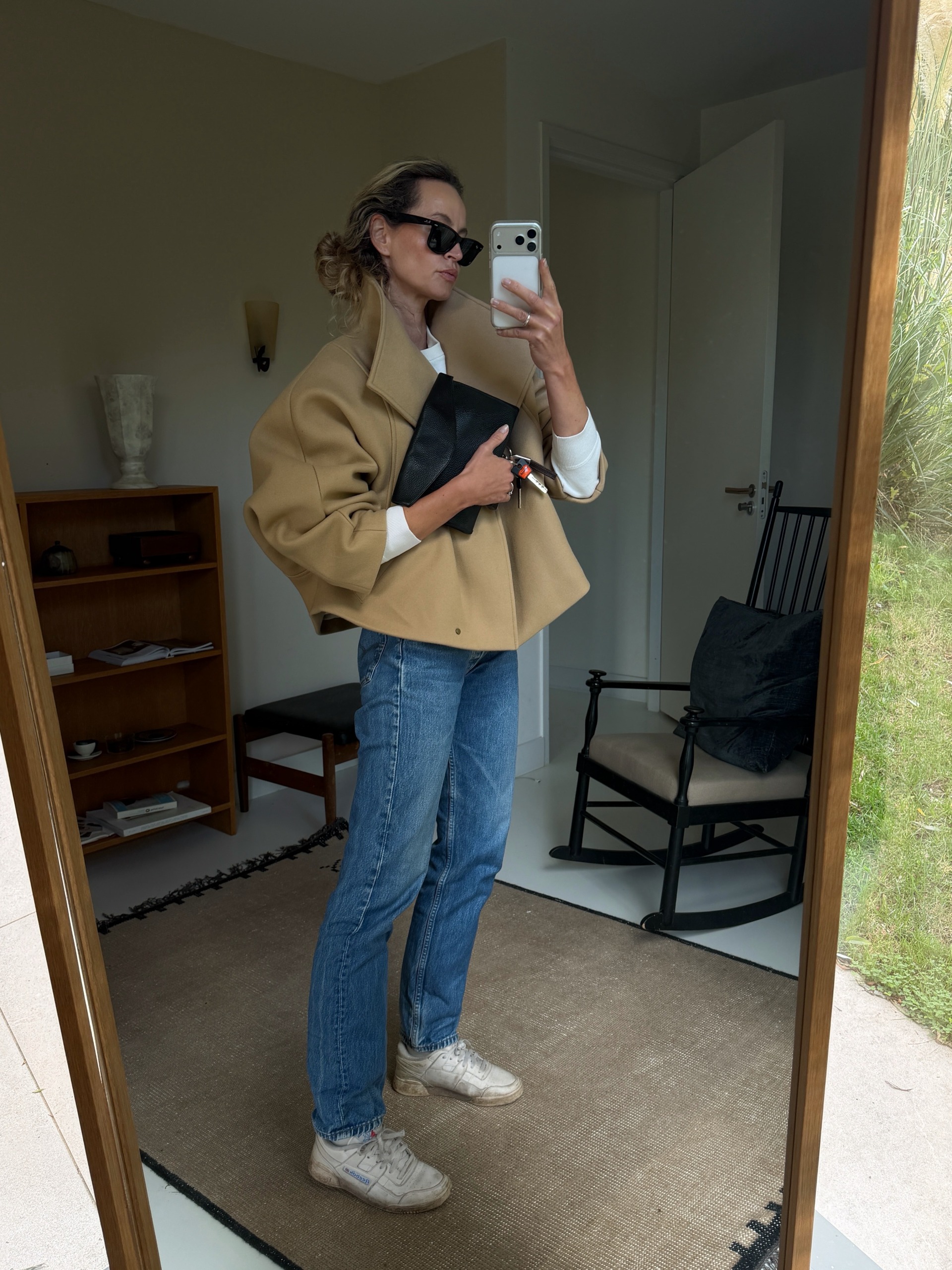 Influencer wearing a cropped camel coat, jeans, and white sneakers