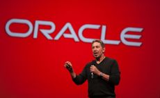 Larry Ellison in front of red background with Oracle sign