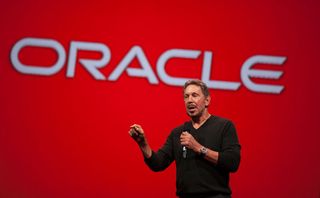 Larry Ellison in front of red background with Oracle sign