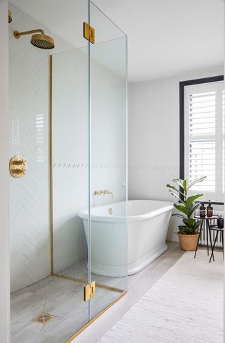 neutral bathroom with white bath and leafy houseplant