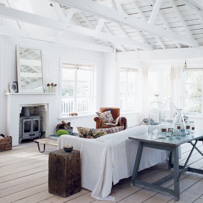 White living room in a cabin with vaulted ceiling and rustic furniture