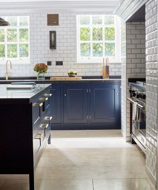 A blue kitchen with beige large stone flooring