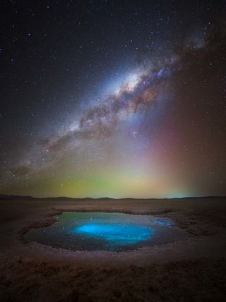 Milky way photographed above a bright blue pool in Atacama Desert, Chile