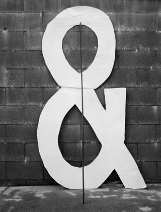 White "&" against a dark grey concrete wall