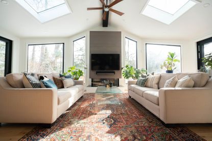 family living room with wall cut outs and lit alcove shelves with neutral sofas and white club armchairs