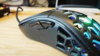 A black AOC GM510 gaming mouse with a hollow honeycomb structure and RGB lighting sitting on a desk