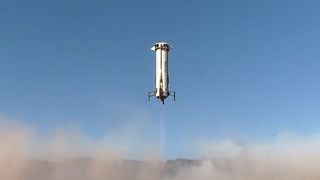 a white-and-blue rocket launches in a sandy desert under clear sunny skies