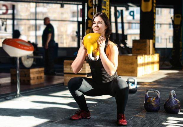 Woman performs goblet squat with kettlebell