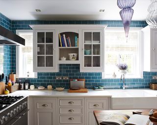 A blue tiled L-shaped kitchen with pale gray cabinetry.