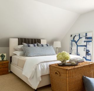 A bedroom with a large cane basket used as a table top and for storing bedroom clutter