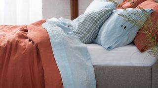Cozy bed with best linen sheets in rust and neutral colors