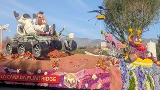 flower-covered parade float showing an astronaut and alien taking a ride on a mars rover