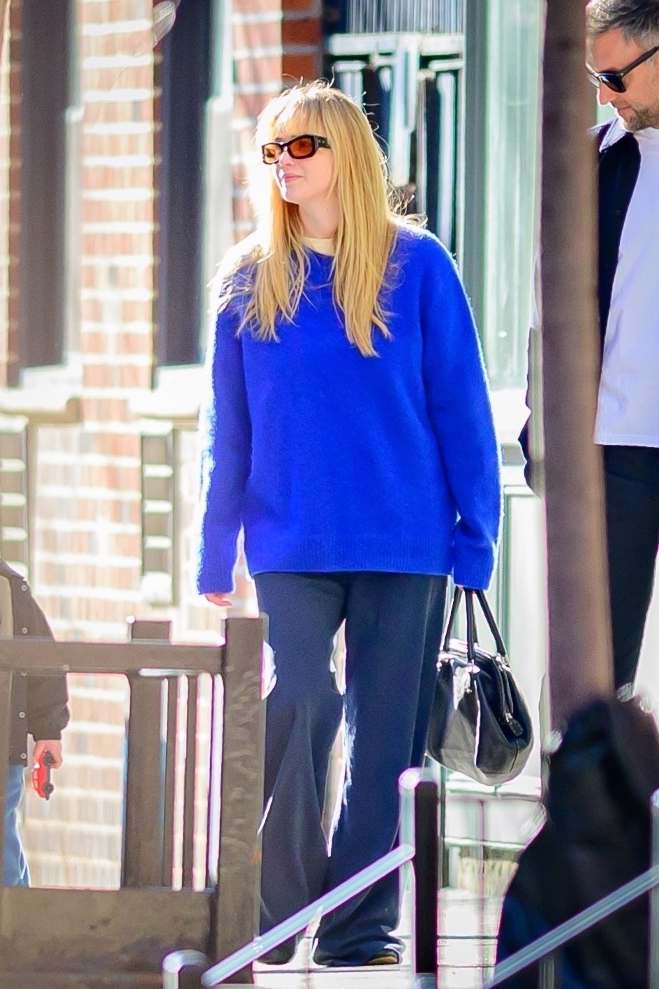 Jennifer Lawrence wearing a cobalt blue sweater, blue jeans, and orange lens sungalsses