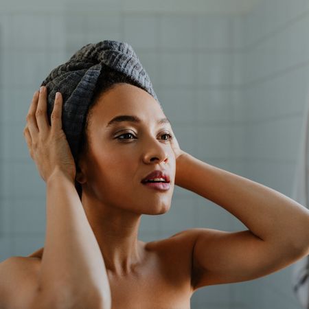 A portrait of a young woman after washing her hair, with a towel wrapped over her head.