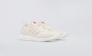 A side view of a white pair of adidas trainers