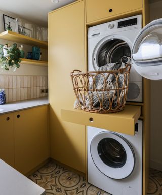 A bright and well designed utility room, with pull out laundry tray, washing machine and tumble dryer, sink and laundry drawers.