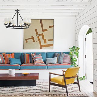 White room with blue sofa cushions and large abstract art work