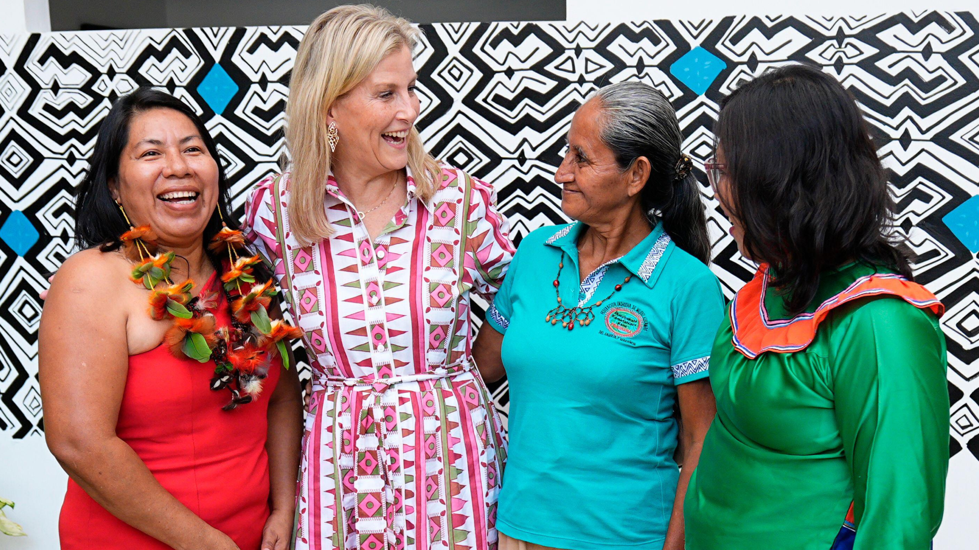 Duchess Sophie wearing a patterned shirt dress with her arms around three ladies and laughing 