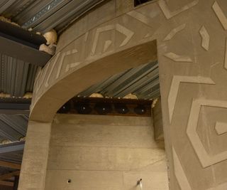 A curved concrete wall with geometric shapes ingrained into it