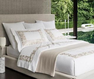 Sferra bedding in a bedroom with a garden view.