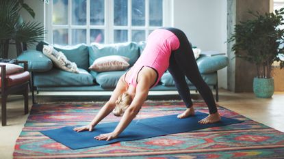 Woman doing downward facing dog yoga pose in living room
