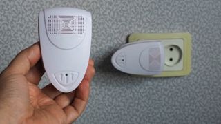 Two ultrasonic pest repelling devices with one plugged in a wall and one held in a hand