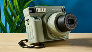 A sage green Fujifilm Instax Wide 400 instant camera