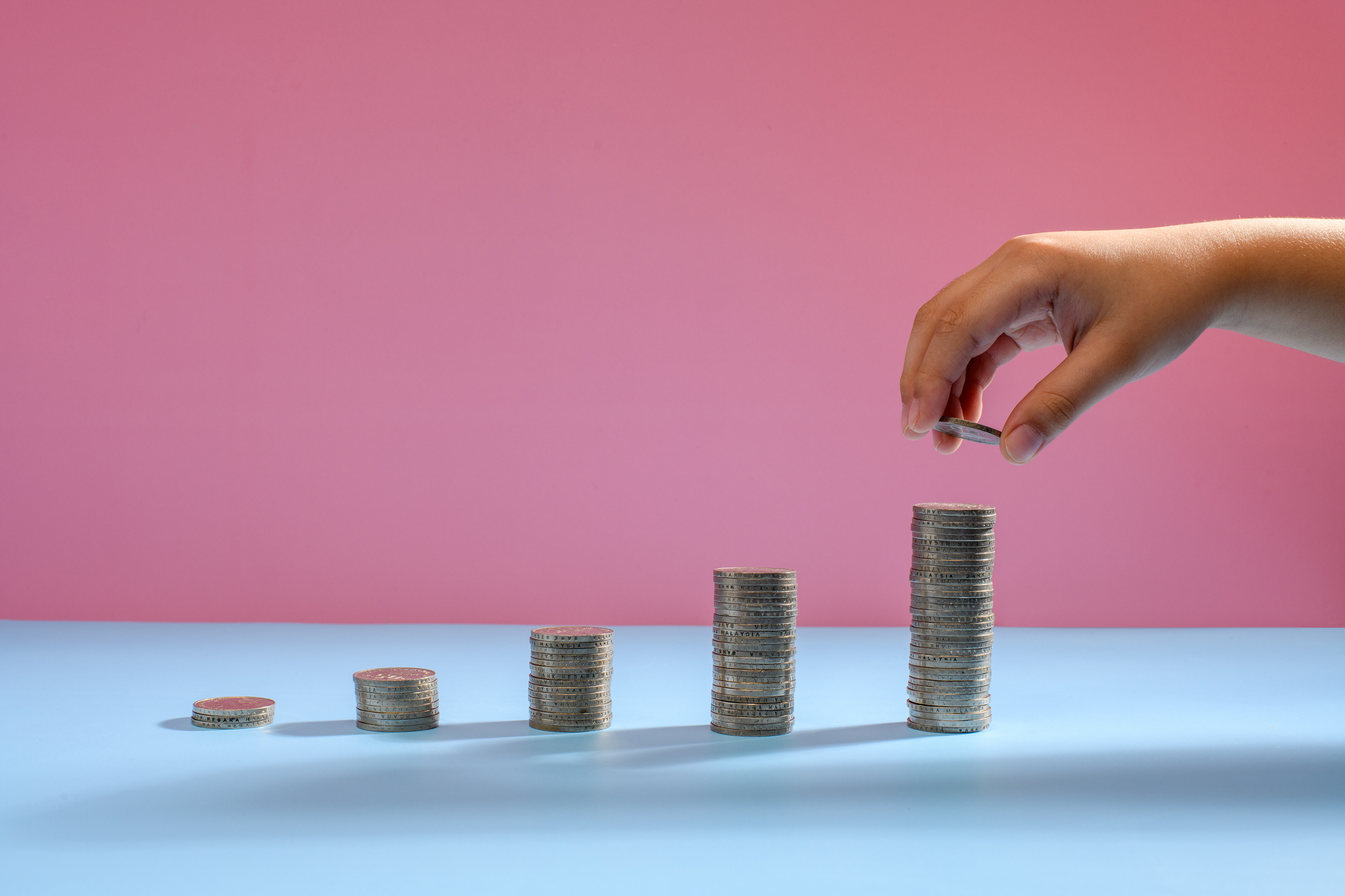 Stack of coins with blue and pink background
