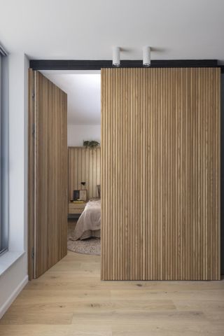 Natural Modern Home by Henkin Shavit Studio - a wood partition leading to a bedroom.