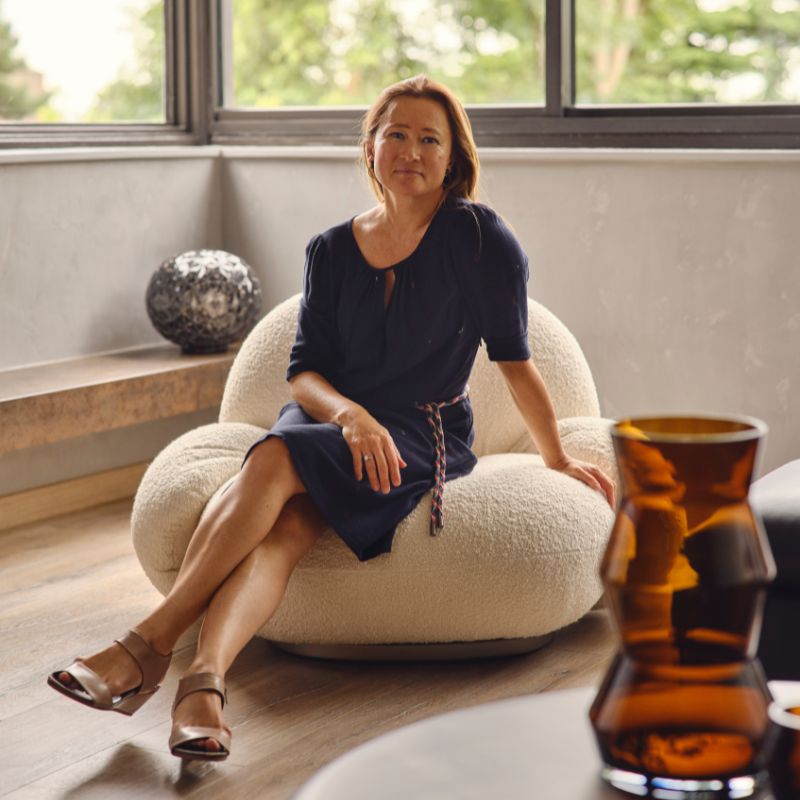 headshot of Caroline Milns, sitting on ivory boucle chair in front of window