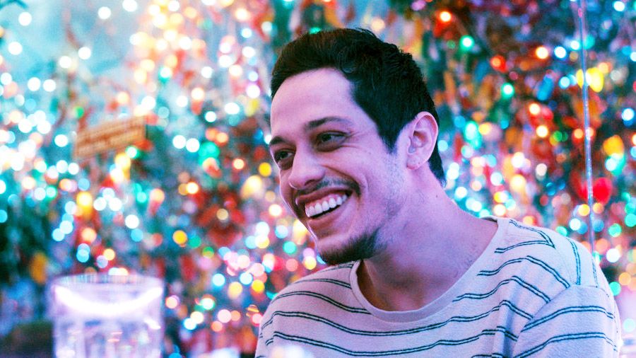 Pete Davidson as Gary, smiling in a brightly lit restaurant, in Meet Cute