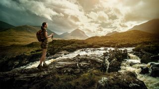 A woman walks across an impressive landscape