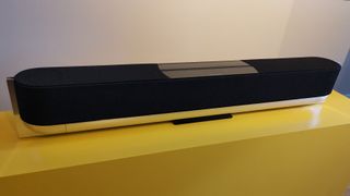 La barre de son Bang & Olufsen Beosound Theatre Dolby Atmos représentée sur une surface jaune