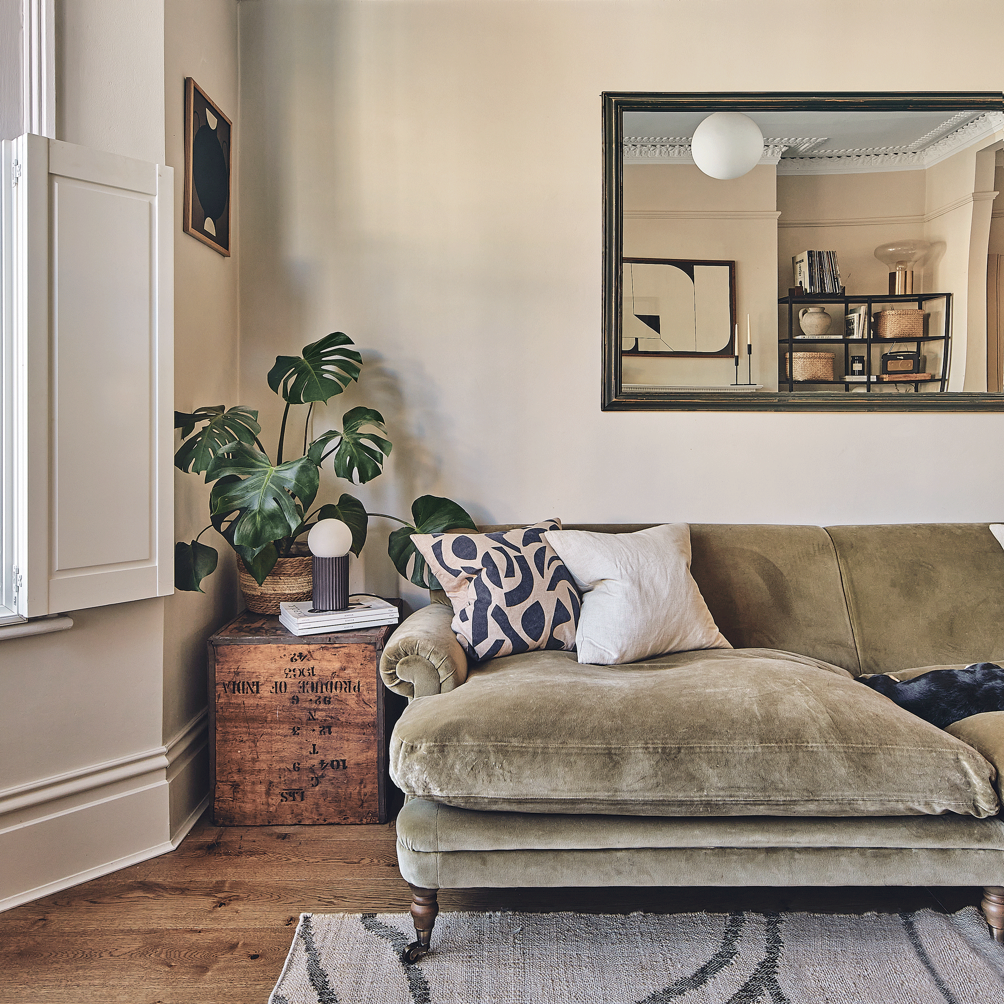 a living room with a green sofa and an upcycled tea crate as a side table with a table lamp and houseplant