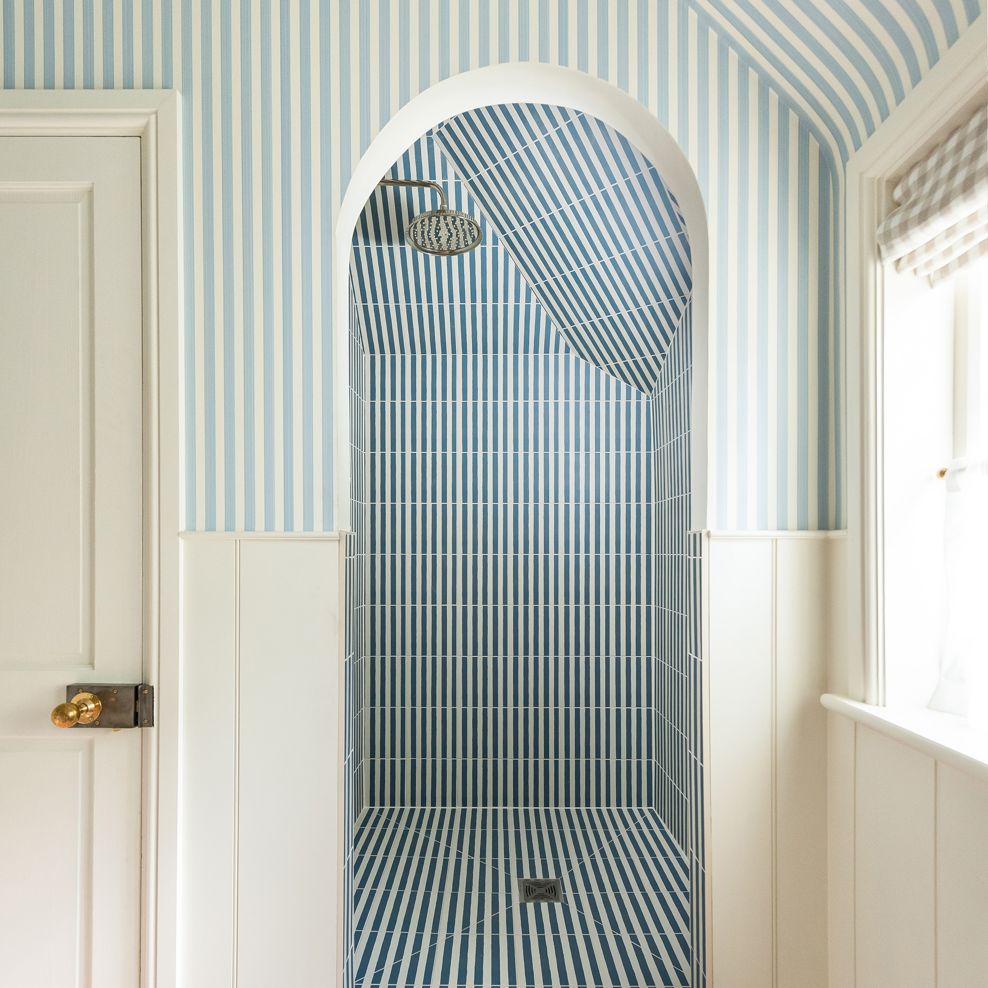 emma ainscough bathroom with shower with blue and white striped tiles and walls with blue and white striped wallpaper